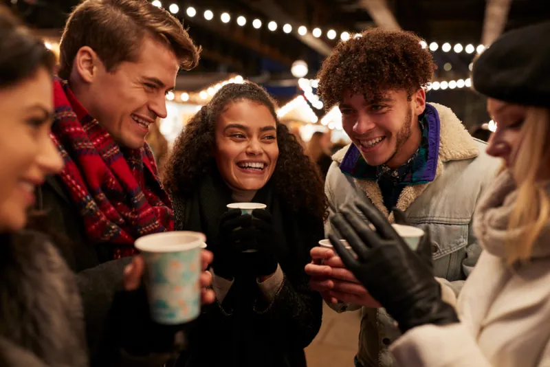 Eine Gruppe von Freunden trinkt Glühwein auf dem Weihnachtsmarkt