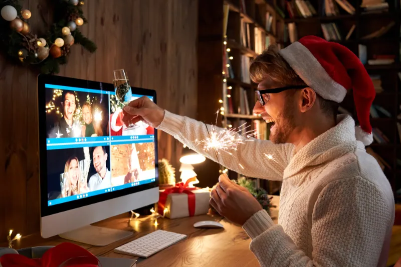 A man celebrates Christmas virtually with colleagues in front of a screen